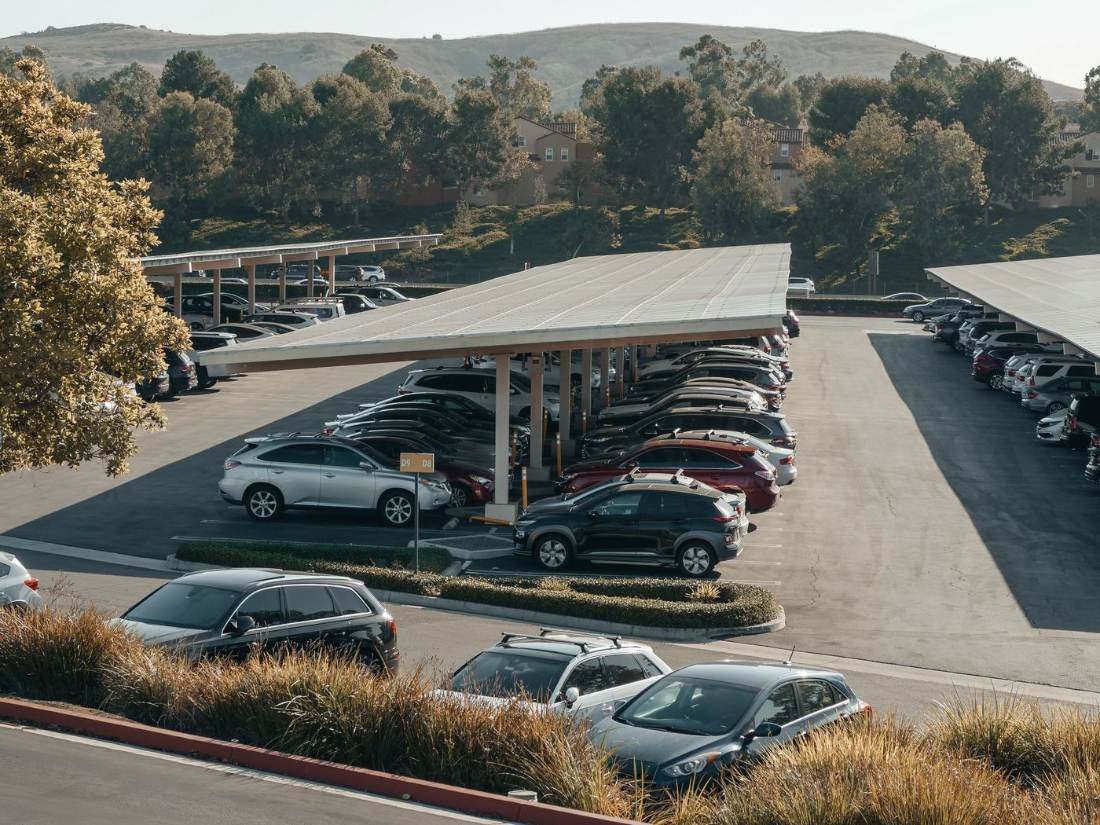 Napelemes carport céges parkolóban, autókkal — fedett parkolóhelyek napelemes tetővel